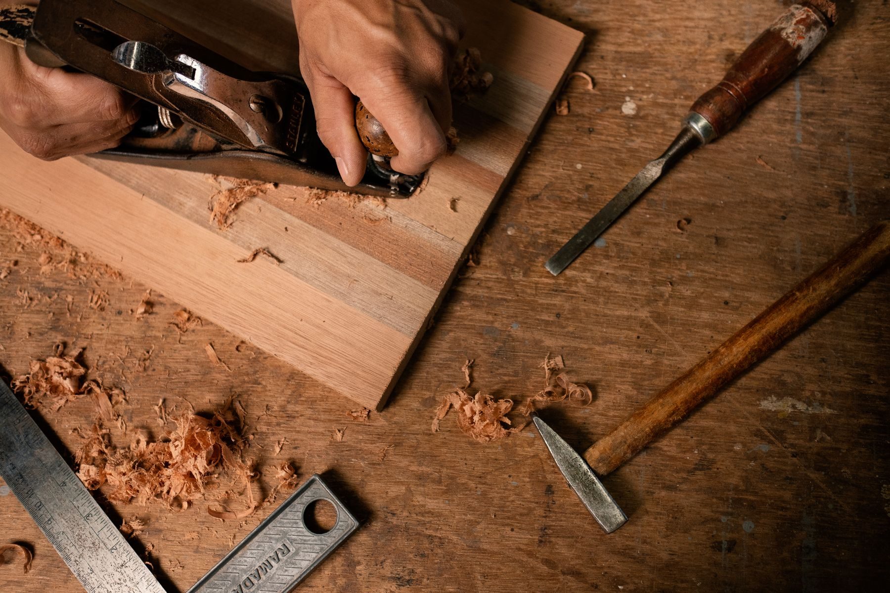 A craftsperson shaping solid wood in the Furnishly workshop